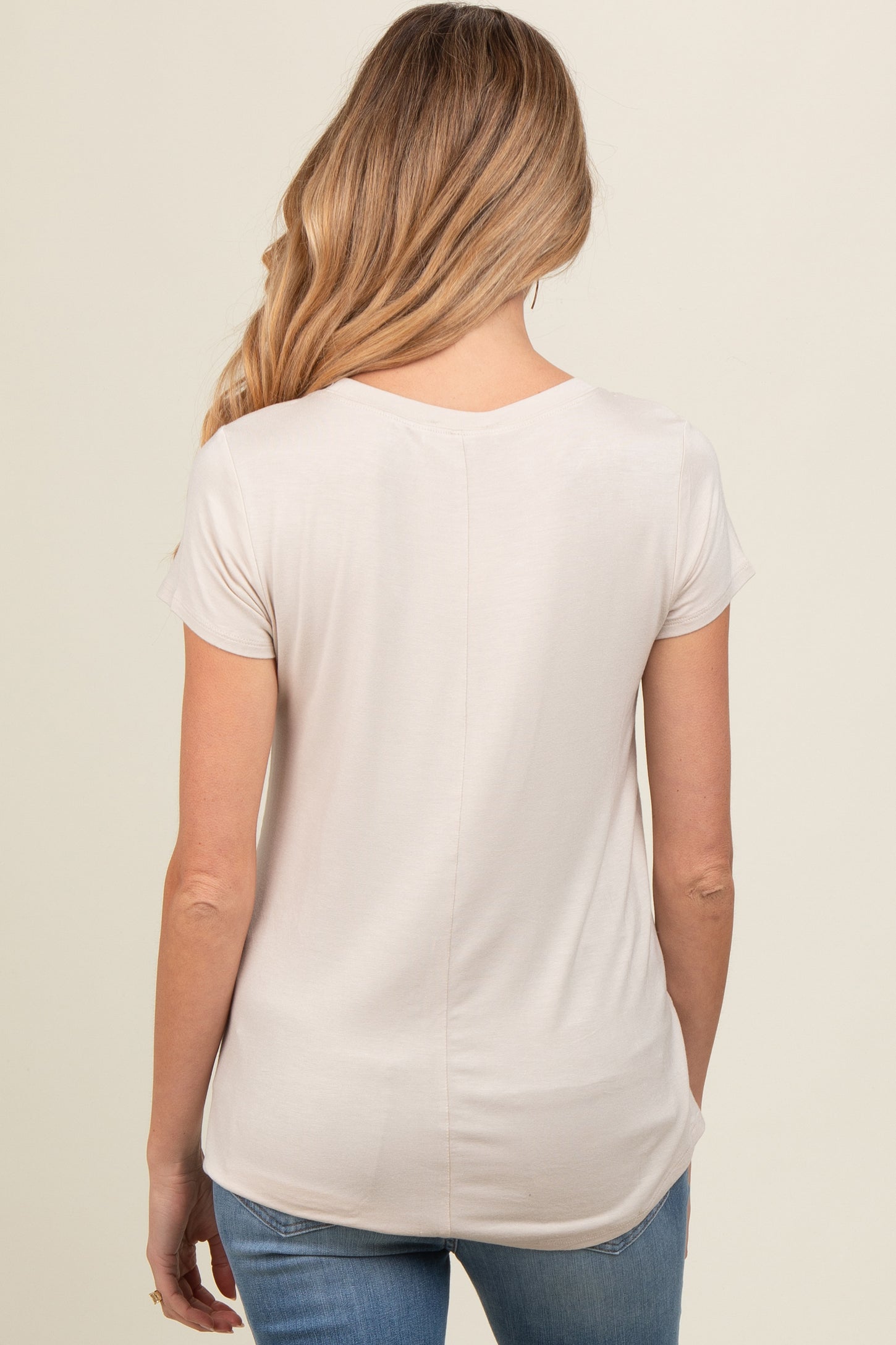 woman wearing a light beige maternity top with short sleeves, view from the back