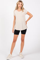 woman wearing a light beige short sleeve top and black bike shorts, standing with one hand on her hip