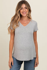 woman wearing a light gray v-neck maternity top with a baby bump and paired with blue jeans