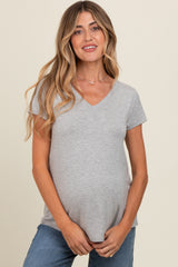 woman wearing a gray v-neck maternity top and holding her baby bump