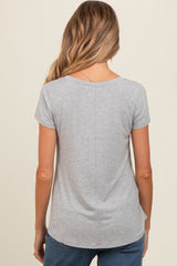 woman wearing a gray short sleeve maternity top, seen from the back, with a curved hem and casual style