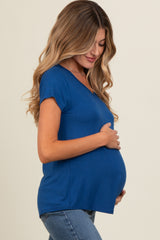 woman wearing a blue short sleeve maternity top and holding her baby bump