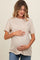 woman wearing a beige short sleeve maternity top and holding her baby bump