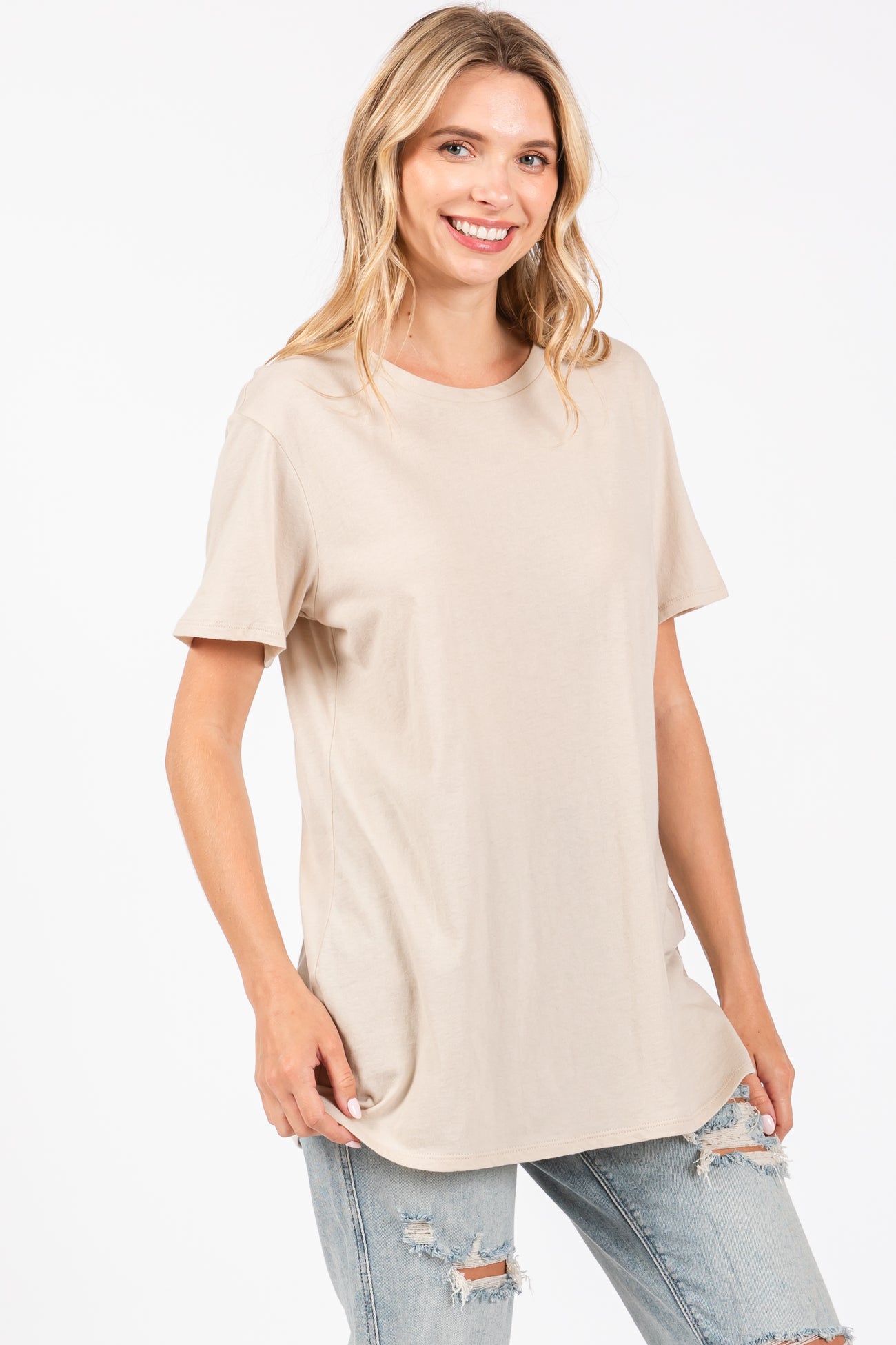 woman wearing a beige short sleeve t-shirt and light blue distressed jeans