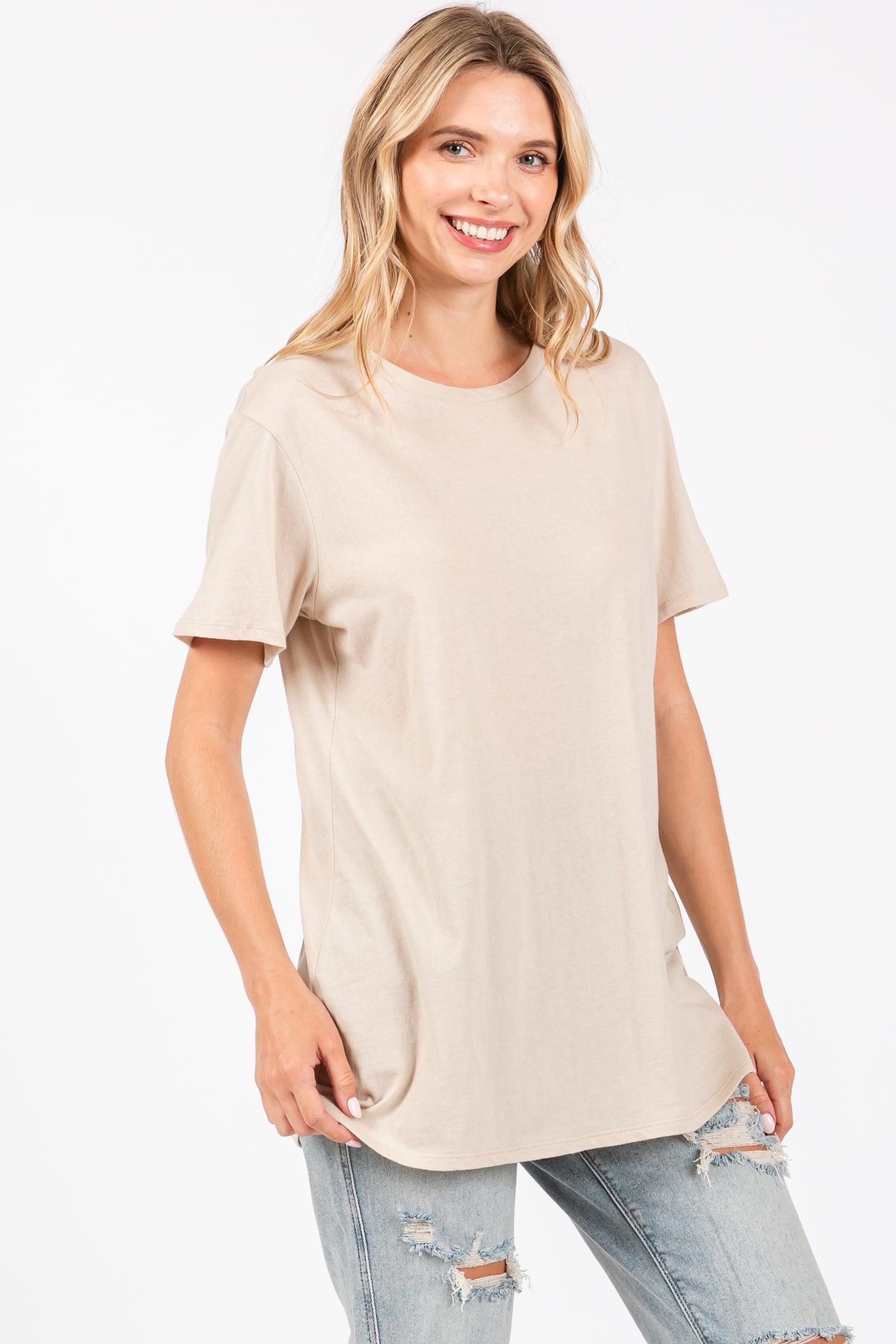 woman wearing a beige short sleeve t-shirt and light blue distressed jeans