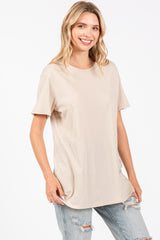 woman wearing a beige short sleeve t-shirt and light blue distressed jeans