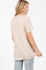 woman wearing a loose-fitting light beige short sleeve t-shirt and light blue distressed jeans, showing the back view