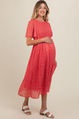 woman wearing a red floral maternity dress with short sleeves and holding her baby bump