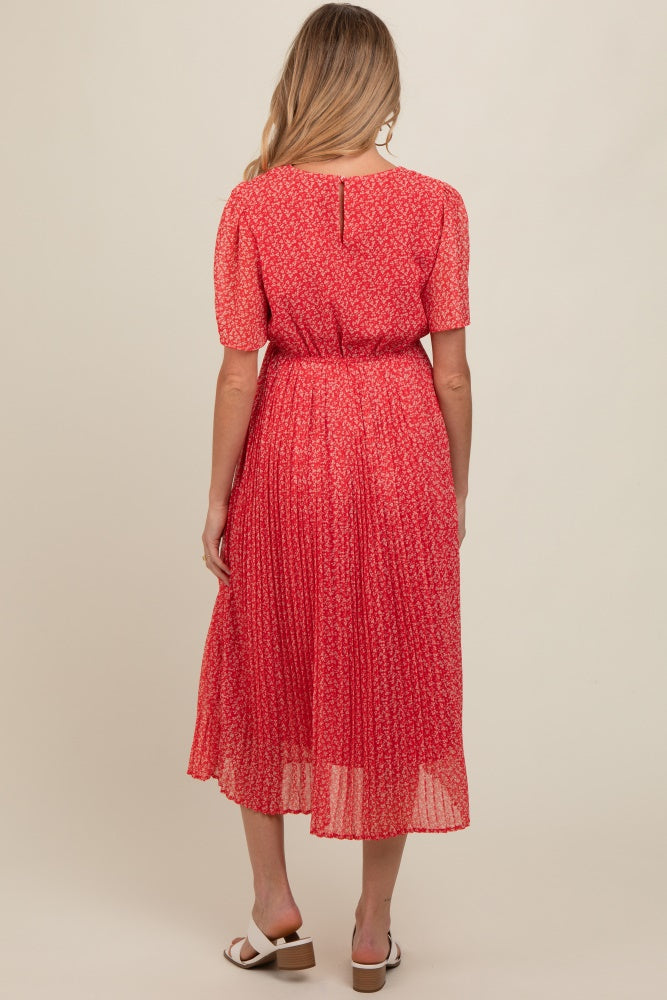 woman wearing a red floral maternity dress with short sleeves and a pleated skirt, showing a baby bump from behind