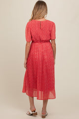 woman wearing a red floral maternity dress with short sleeves and a pleated skirt, showing a baby bump from behind