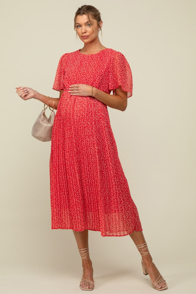 woman wearing a red floral maternity dress with short flutter sleeves and holding her baby bump