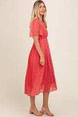 woman wearing a red floral midi dress with short sleeves and a pleated skirt, posed in profile