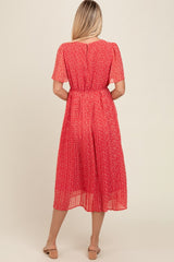 woman wearing a red floral midi dress with short sleeves and a pleated skirt, viewed from the back