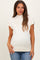 woman wearing a light beige maternity top with a mock neck and cap sleeves, showing her baby bump