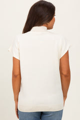 woman wearing a cream short sleeve maternity sweater with a mock neck, showing the back view
