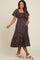 woman wearing a black floral maternity dress with puff sleeves and a flowing skirt, holding her baby bump