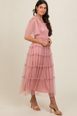 woman wearing a light pink tiered midi dress with puff sleeves and ruffle details, standing in profile