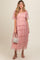 woman wearing a pink tiered tulle maternity dress with puff sleeves and holding a pearl-accented handbag