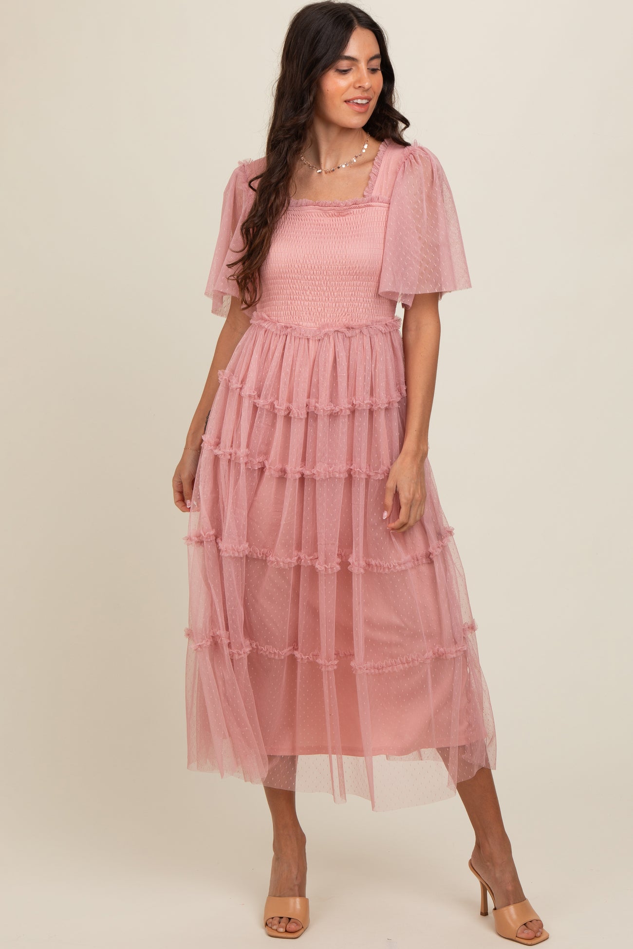 woman wearing a pink tiered midi dress with puff sleeves and a smocked bodice