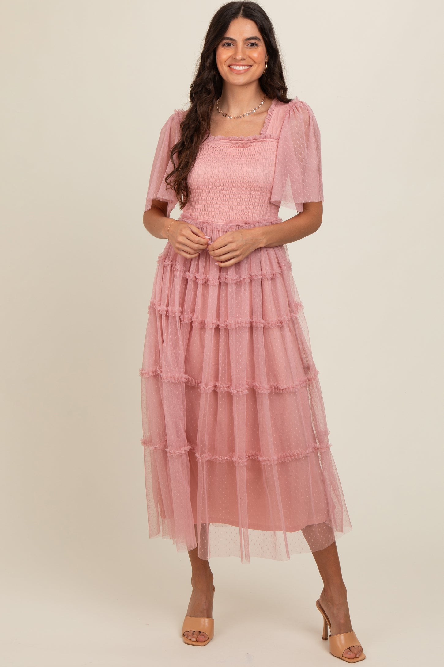woman wearing a pink tiered tulle dress with puff sleeves and a smocked bodice