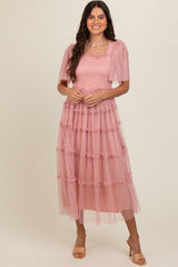 woman wearing a pink tiered tulle dress with puff sleeves and a smocked bodice