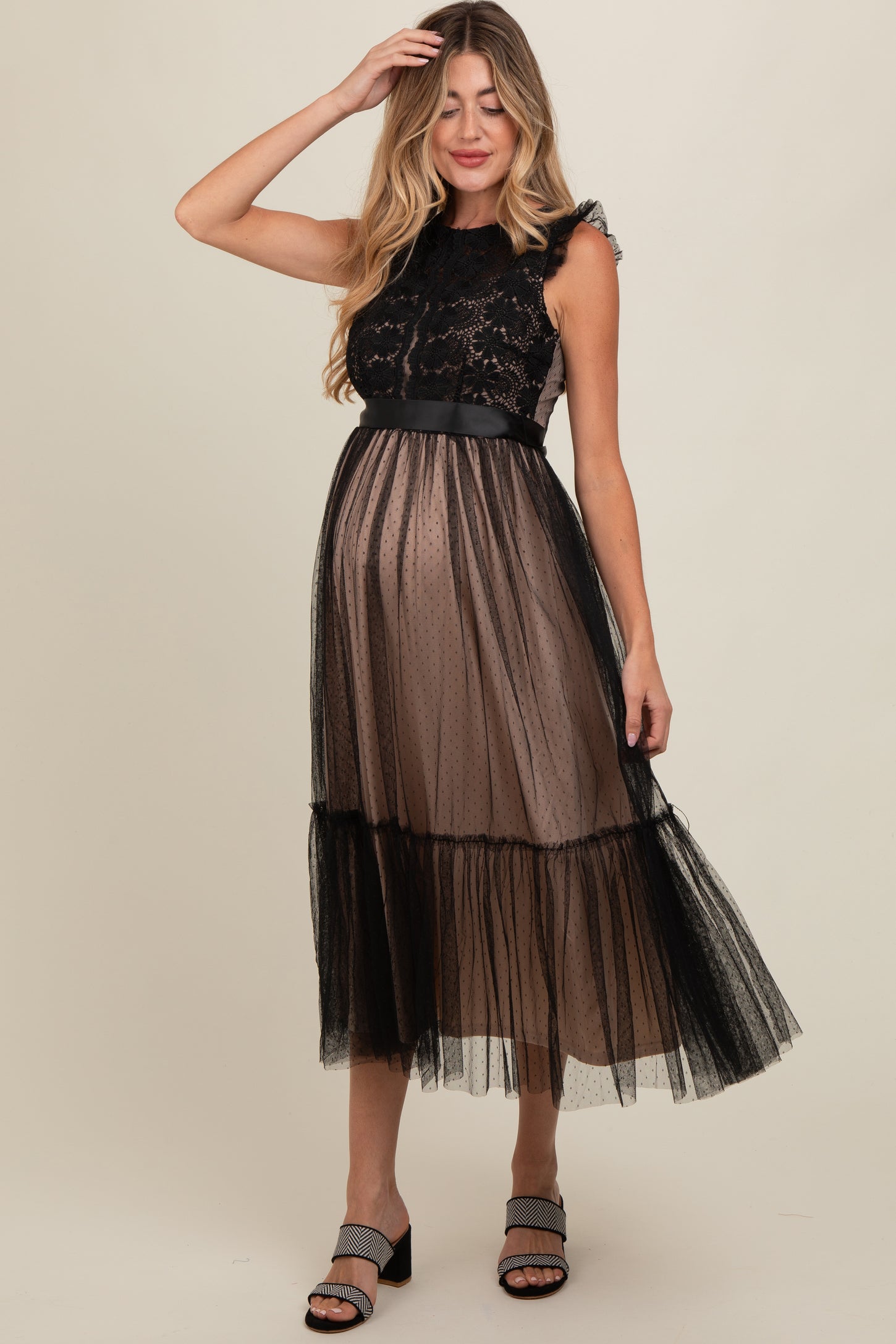 woman wearing a black maternity dress with lace bodice and tulle skirt, showcasing her baby bump