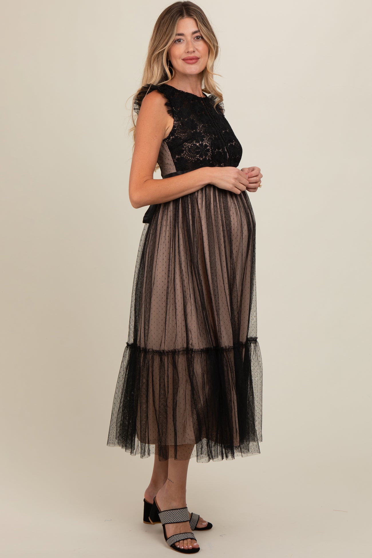 woman wearing a black lace and tulle maternity dress with a baby bump visible