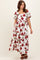woman wearing a white floral maxi dress with red roses and puff sleeves, standing and looking down