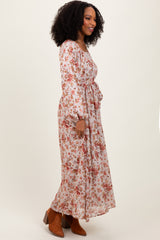 woman wearing a long sleeve floral maxi dress with a cinched waist and flowy silhouette, paired with ankle booties