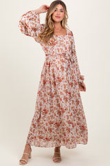 woman wearing a floral print maternity maxi dress with balloon sleeves and a cinched waist, smiling and posing