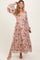 woman wearing a floral print maternity maxi dress with balloon sleeves and a cinched waist, smiling and posing