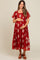 woman wearing a red maternity dress with white floral embroidery and holding her baby bump