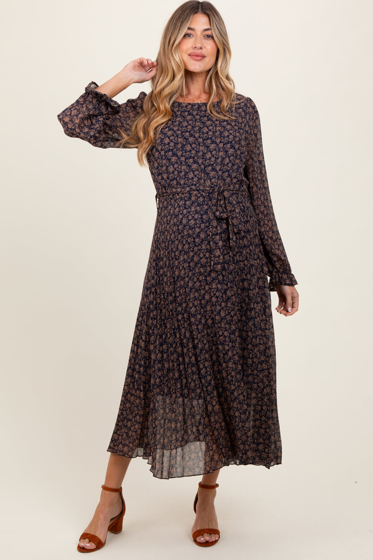 woman wearing a navy floral long sleeve maternity dress with a tie waist and flowing skirt
