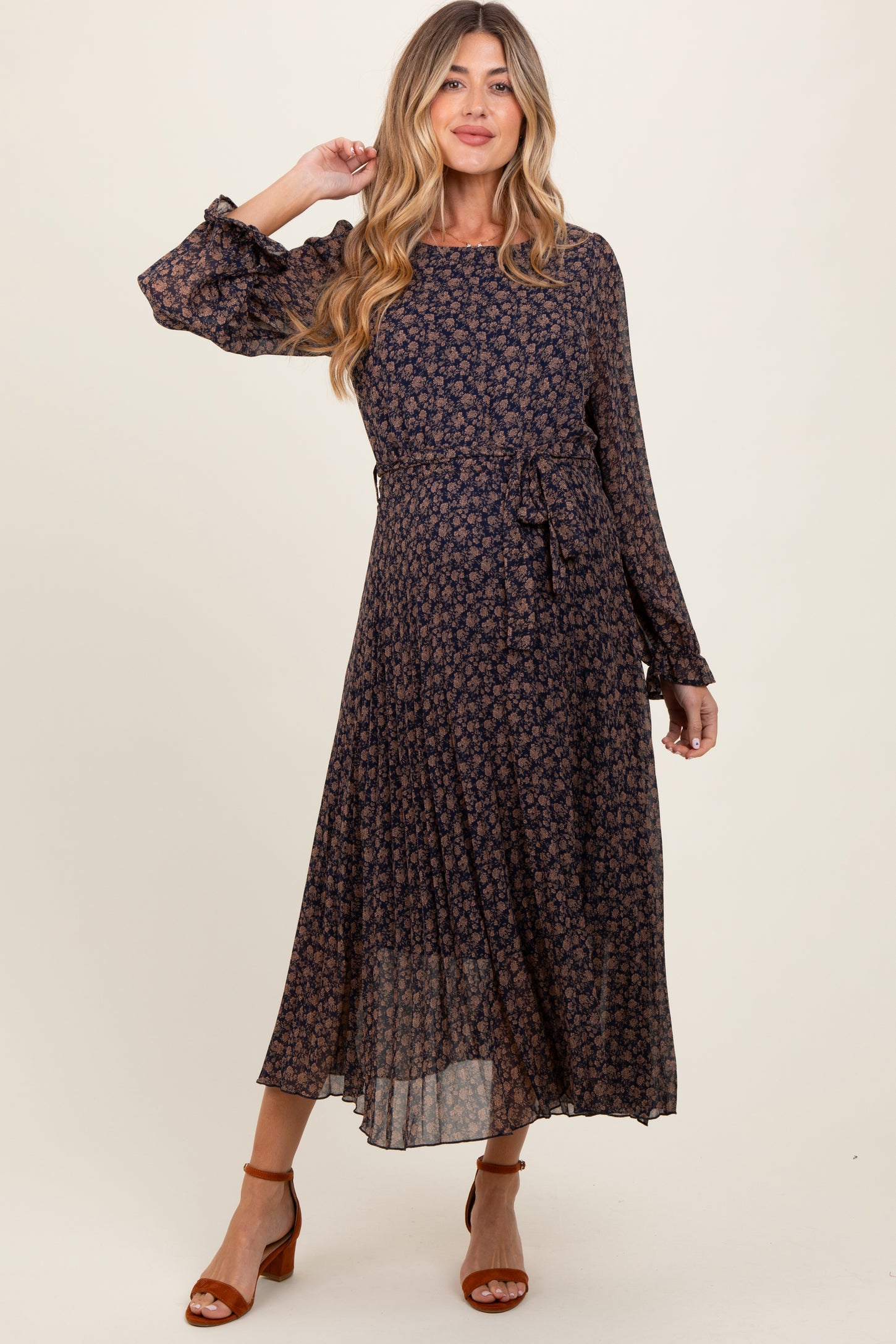 woman wearing a navy floral long sleeve maternity dress with a tie waist and flowing skirt
