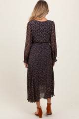 woman wearing a navy blue floral maternity maxi dress with long sleeves and a cinched waist, viewed from the back