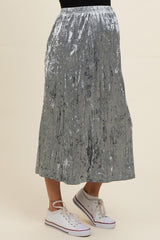 woman wearing a silver velvet maternity skirt with pleats and sneakers, showcasing a baby bump