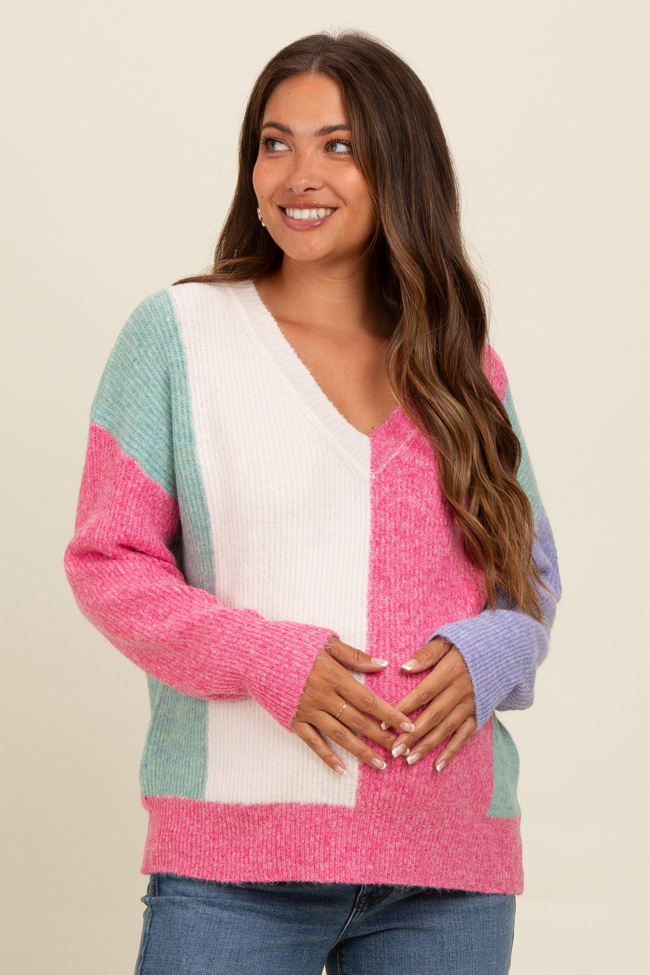 woman wearing a colorful maternity sweater with a v-neck and holding her baby bump