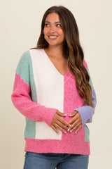woman wearing a colorful maternity sweater with a v-neck and holding her baby bump