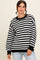 woman wearing a black and white striped oversized sweater with a relaxed fit and long sleeves