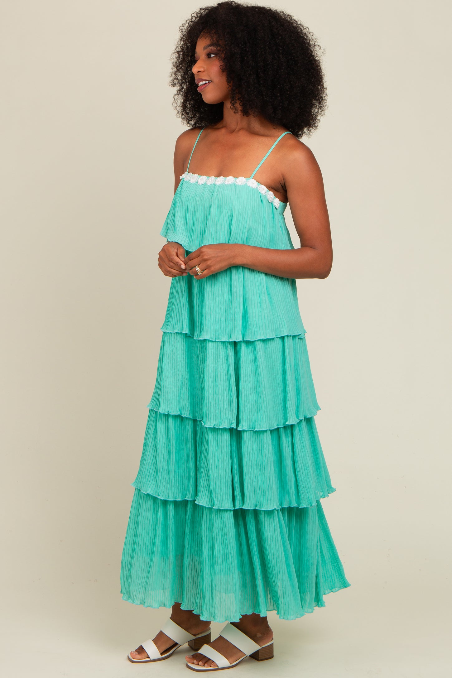 woman wearing a tiered mint green maxi dress with spaghetti straps and lace trim, styled with white sandals