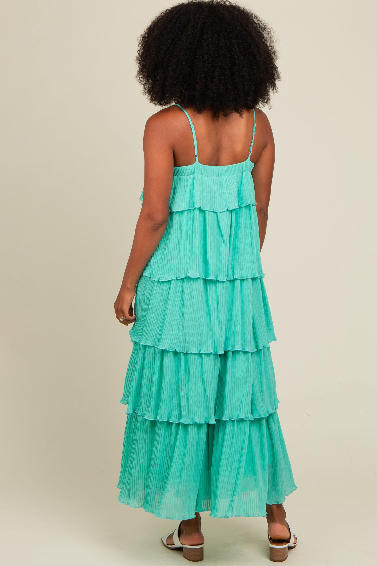 woman wearing a tiered aqua maxi dress with thin straps and pleated detailing, viewed from the back