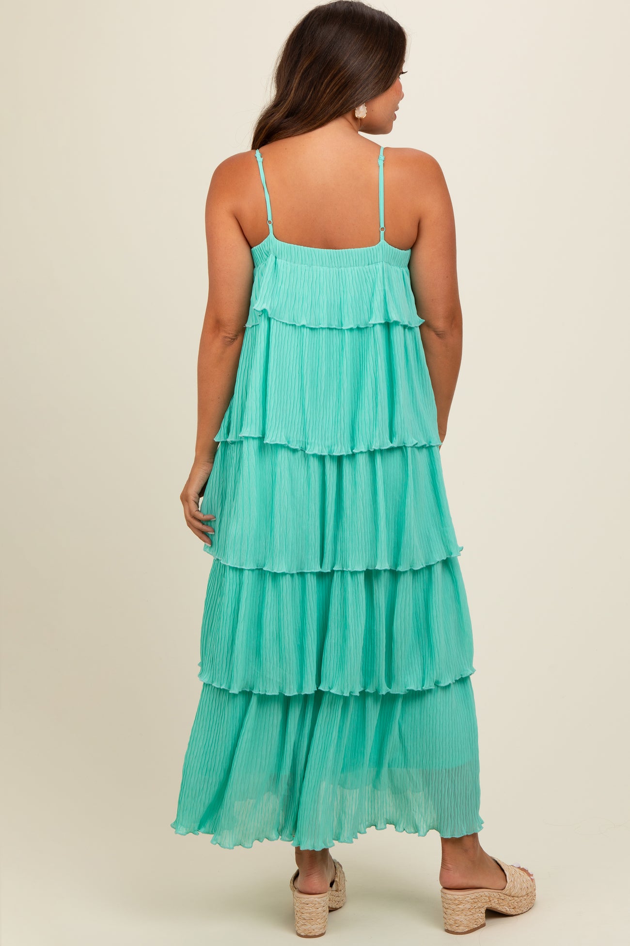 woman wearing a turquoise tiered maxi maternity dress with adjustable straps and a pleated design