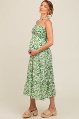 woman wearing a green leafy print maternity dress with a halter neck and baby bump.visible