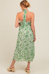woman wearing a green floral halter neck maternity dress with a smocked back and flowing skirt
