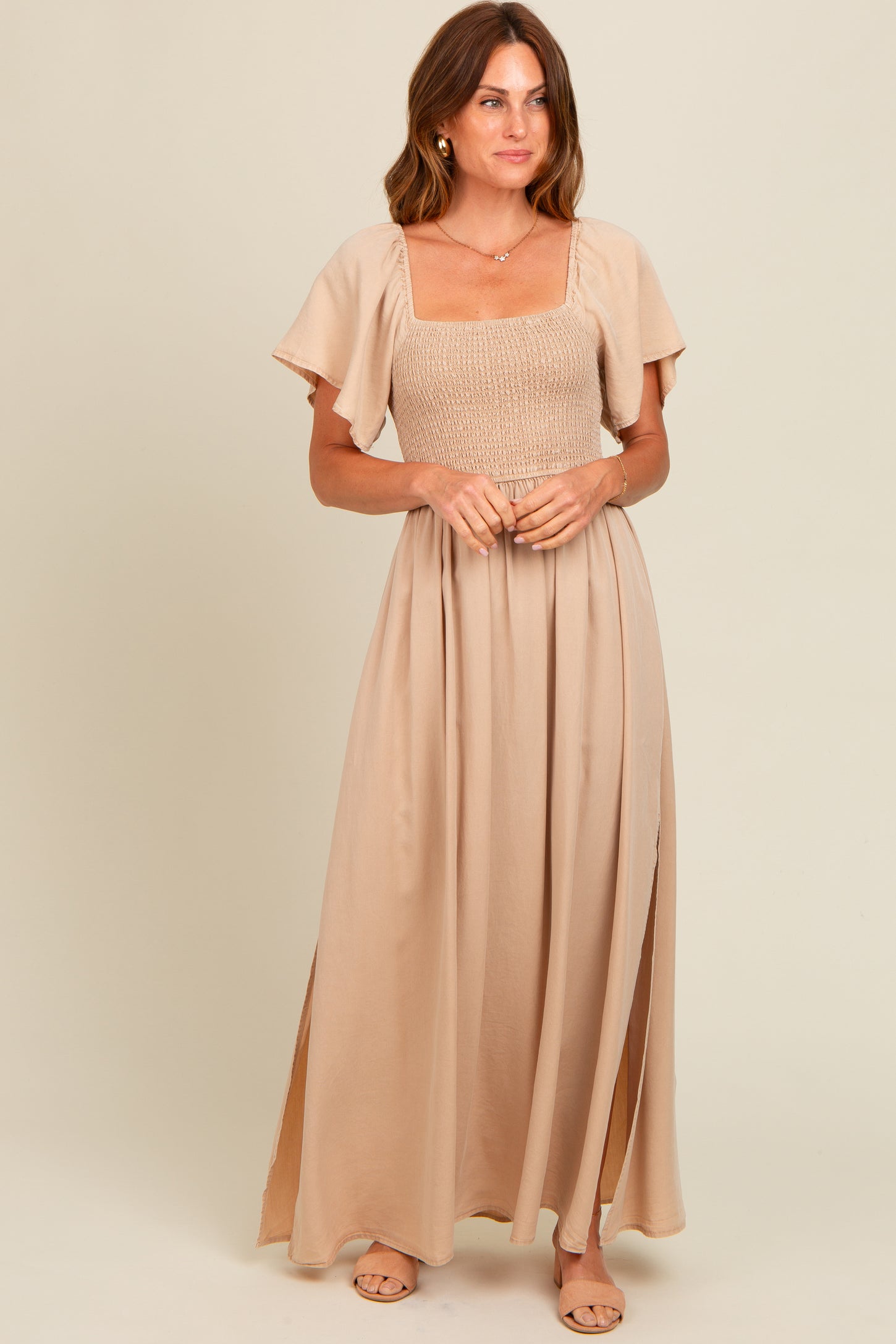 woman wearing a beige maxi dress with a smocked bodice and flutter sleeves