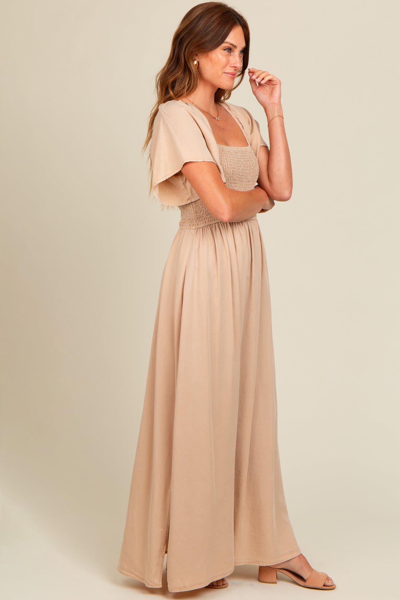 woman wearing a light beige maxi dress with a smocked bodice and flutter sleeves