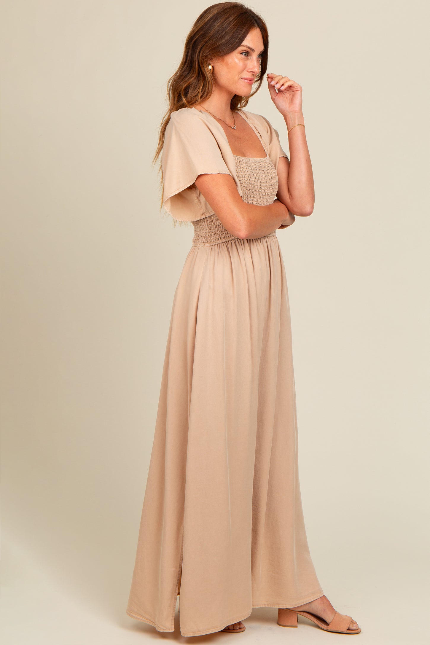 woman wearing a light beige maxi dress with a smocked bodice and flutter sleeves