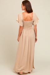 woman wearing a back view of a beige maxi dress with smocked bodice and flutter sleeves