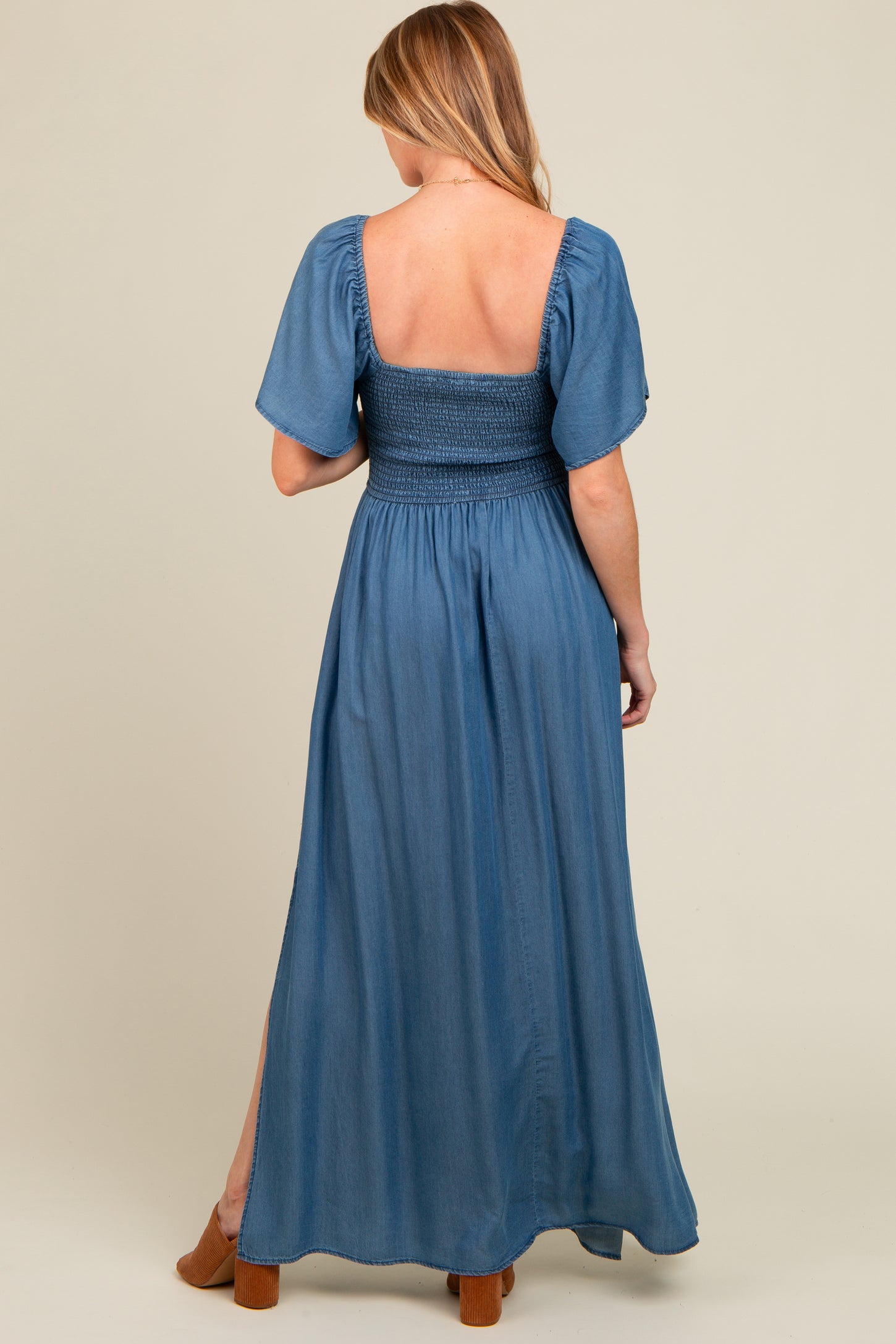 woman wearing a blue maternity maxi dress with a smocked bodice and puff sleeves, showing a baby bump from the back