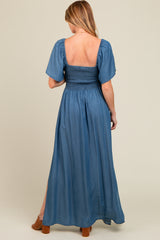woman wearing a blue maternity maxi dress with a smocked bodice and puff sleeves, showing a baby bump from the back